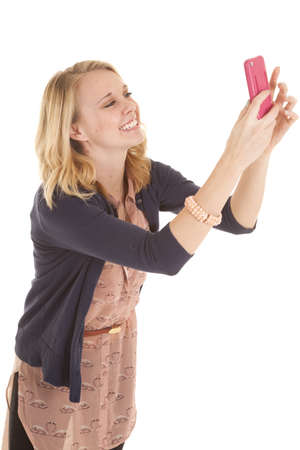 A woman with a smile on her face holding up her cell phone.の写真素材