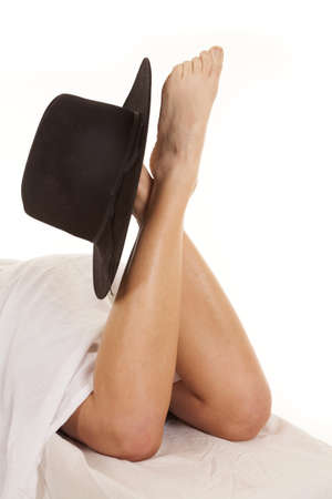A woman has her legs coming out of a sheet with a cowboy hat on them.の写真素材