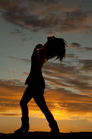 a silhouette of a woman standing with a beautiful sunset in the background.の写真素材