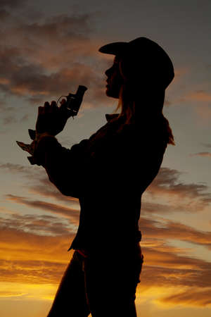 A silhouette of a woman blowing on the end of her gun.の写真素材
