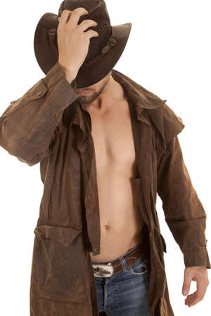 a man holding on to his western hat in his duster without a shirt.の写真素材