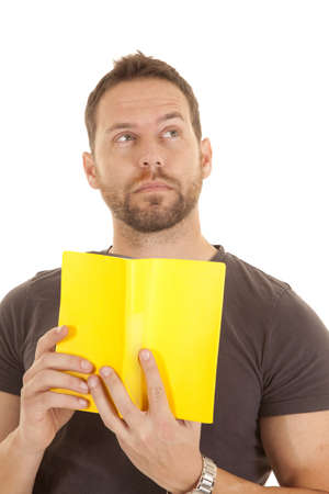 A man holding up his book with a thoughtful expression on his face.の写真素材