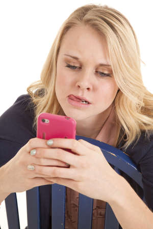 A woman thinking really hard while she is text-ing on her cell phone.の写真素材