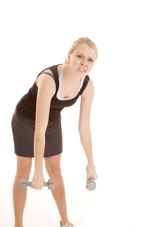 A woman leaning over with a tired expression and she can not lift her weights.の写真素材