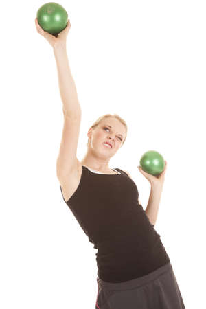 A woman with a strained expression on her face as she is lifting weighted balls.の写真素材