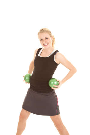 A woman with a smile on her face holding on to two green weighted balls on her hips.の写真素材