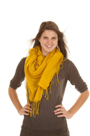 A woman standing with her hands on her hips with a smile on her face and the wind blowing her hair.の写真素材