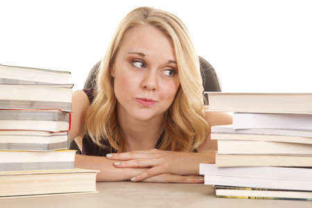 a woman looking to the side with a stack of books around her.の写真素材