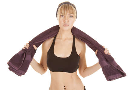 A woman with a serious expression on her face holding her purple towel after a workout.の写真素材