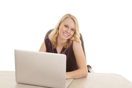 A woman smiling while working on her laptop.の写真素材