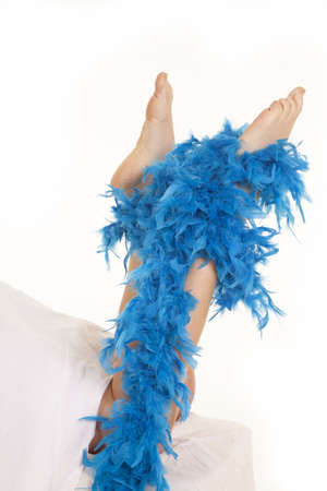 A woman has her feet coming out from under the covers with a boa on them.の写真素材
