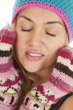 A woman with her eyes closed and her gloves on her face.の写真素材