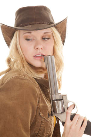 A cowgirl holding on to her weapon up by her mouth looking back.の写真素材