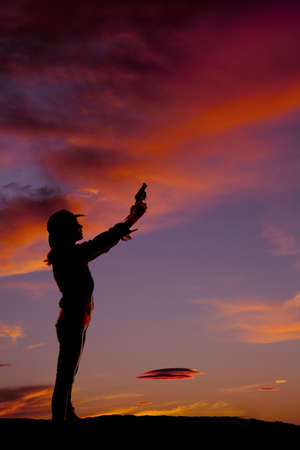 A silhouette of a woman holding on to her pistolの写真素材