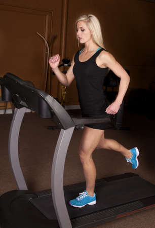 A woman with a serious expression and running on her treadmill.の写真素材