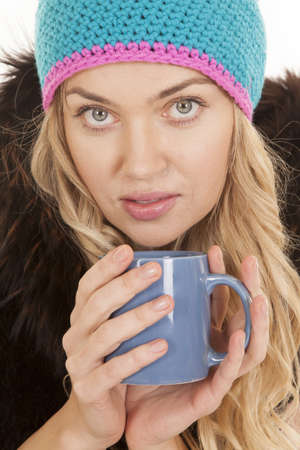 A woman with a serious expression holding on to a mug in her coat.の写真素材