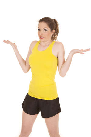 A woman in a yellow workout outfit with her hands up.の写真素材