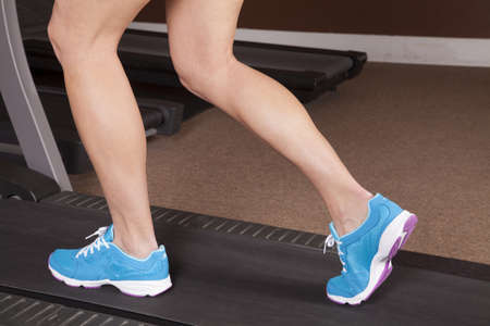 A close up of a woman running on a treadmill.の写真素材