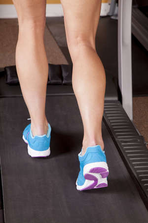 A close up of a woman running a treadmill.の写真素材