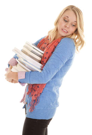 A woman with a stack of books looking down trying not to drop themの写真素材