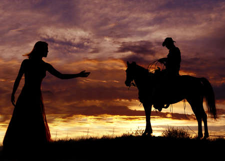 A cowboy is sitting on a horse in the sunset swinging a rope.の写真素材