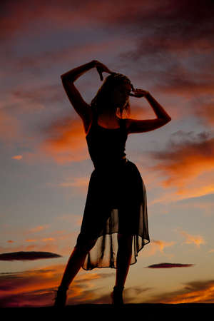 A silhouette of a woman standing in her dress in the night sky.の写真素材