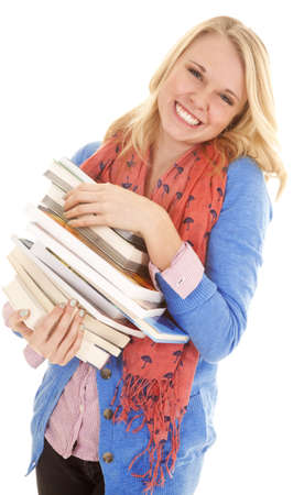 A woman with a smile on her face holding on to a stack of booksの写真素材