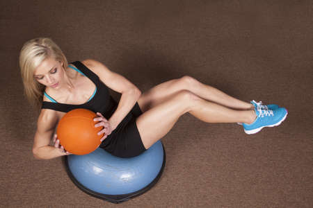 a woman sitting and doing a twist with a weighted ballの写真素材