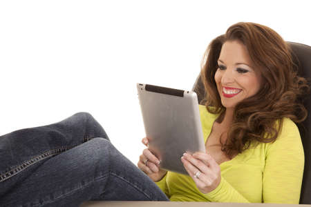 A woman in a yellow shirt has a big smile and working on a tablet.の写真素材