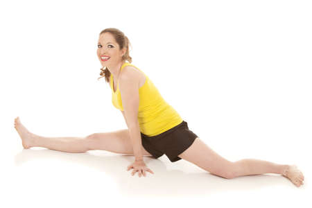 A woman in a yellow tank top doing the splitsの写真素材