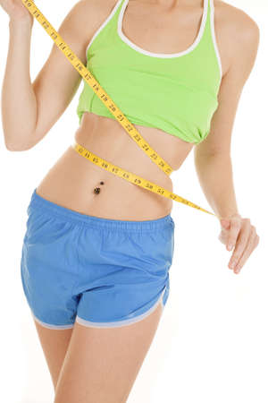 A woman in her fitness outfit measuring her waist with a measuring tape.の写真素材