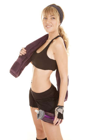 A woman with a towel over her shoulder with a big smile on her face holding on to her water bottle.の写真素材