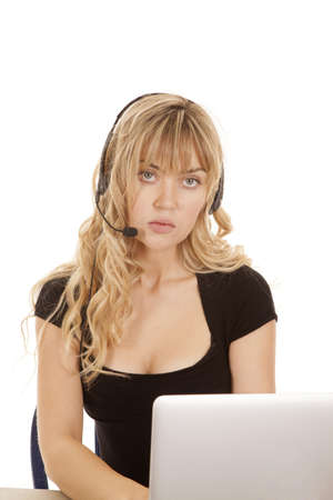 a woman with her headset on with a serious expression on her face working on her computer.の写真素材