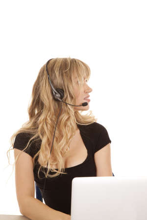 A woman working on her computer with a smile on her face looking to the side.の写真素材