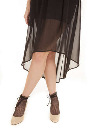 A woman standing with her legs crossed in her skirt and shoes.の写真素材