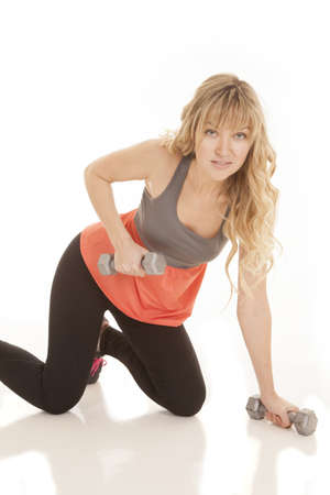 a woman with a smile working out her arms while on her knees.の写真素材