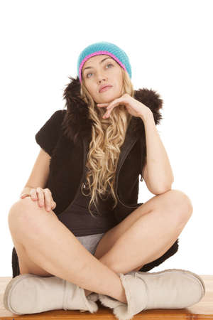 A woman sitting on a bench looking up in her hat and furry boots.の写真素材