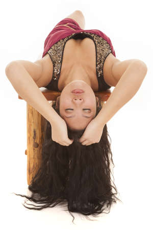 A woman laying on a bench with her hands in her hair with her eyes closed.の写真素材