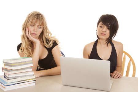 Two women sitting at a table with books and a laptop learing.の写真素材