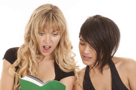 Two women reading and learning, but one of them is shocked by what she is reading.の写真素材