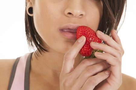 a close up of a woman's mouth with a strawberry up close to her lipsの写真素材
