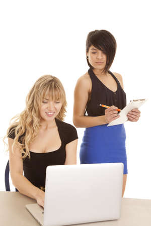 A woman taking notes and one working on the computer.の写真素材