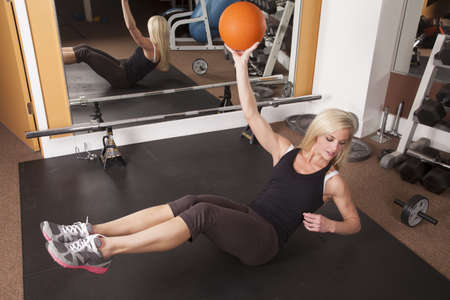 A woman doing a crunch while holding on to a weighted ball.の写真素材