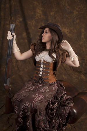 A woman in her vintage western dress holding on to her shotgun.の写真素材