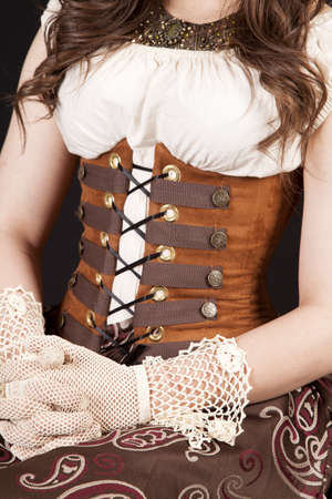 A close up of a woman in her corset and gloves sitting proper.の写真素材