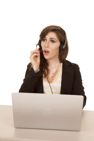 A woman sitting at her desk talking on her headset working.の写真素材