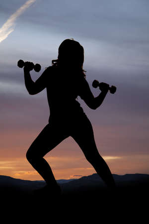 A woman working out outdoors with a beautiful sunset behind her.の写真素材