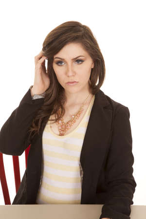 a woman sitting at a desk with a serious expression on her face pulling hair backの写真素材