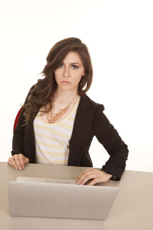 A woman sitting at a desk with her laptop with a serious expressionの写真素材