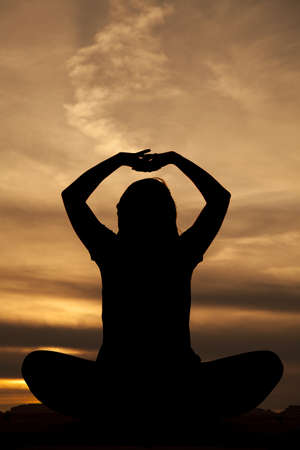 A silhouette of a woman sitting and doing a yoga stretch.の写真素材